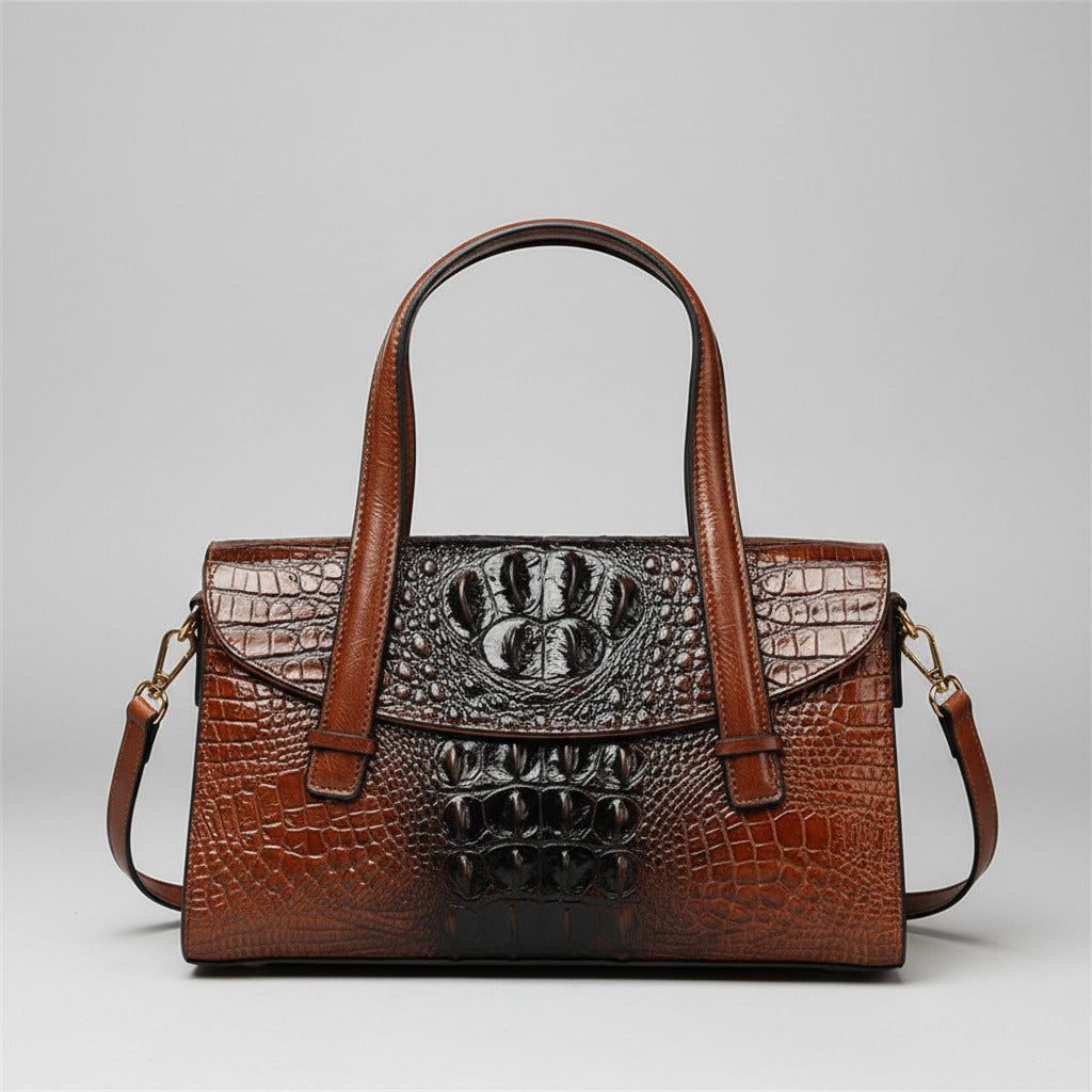 Brown leather handbag with crocodile texture held against a brick wall.
