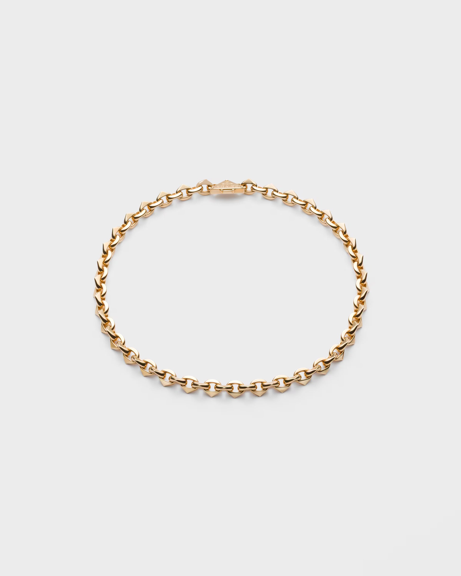 Gold chain bracelet on a light gray background
